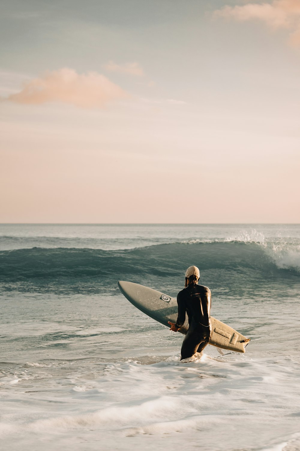 a man in a wet suit carrying a surfboard into the ocean