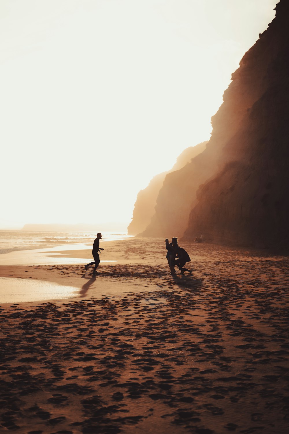 a couple of people standing on top of a sandy beach