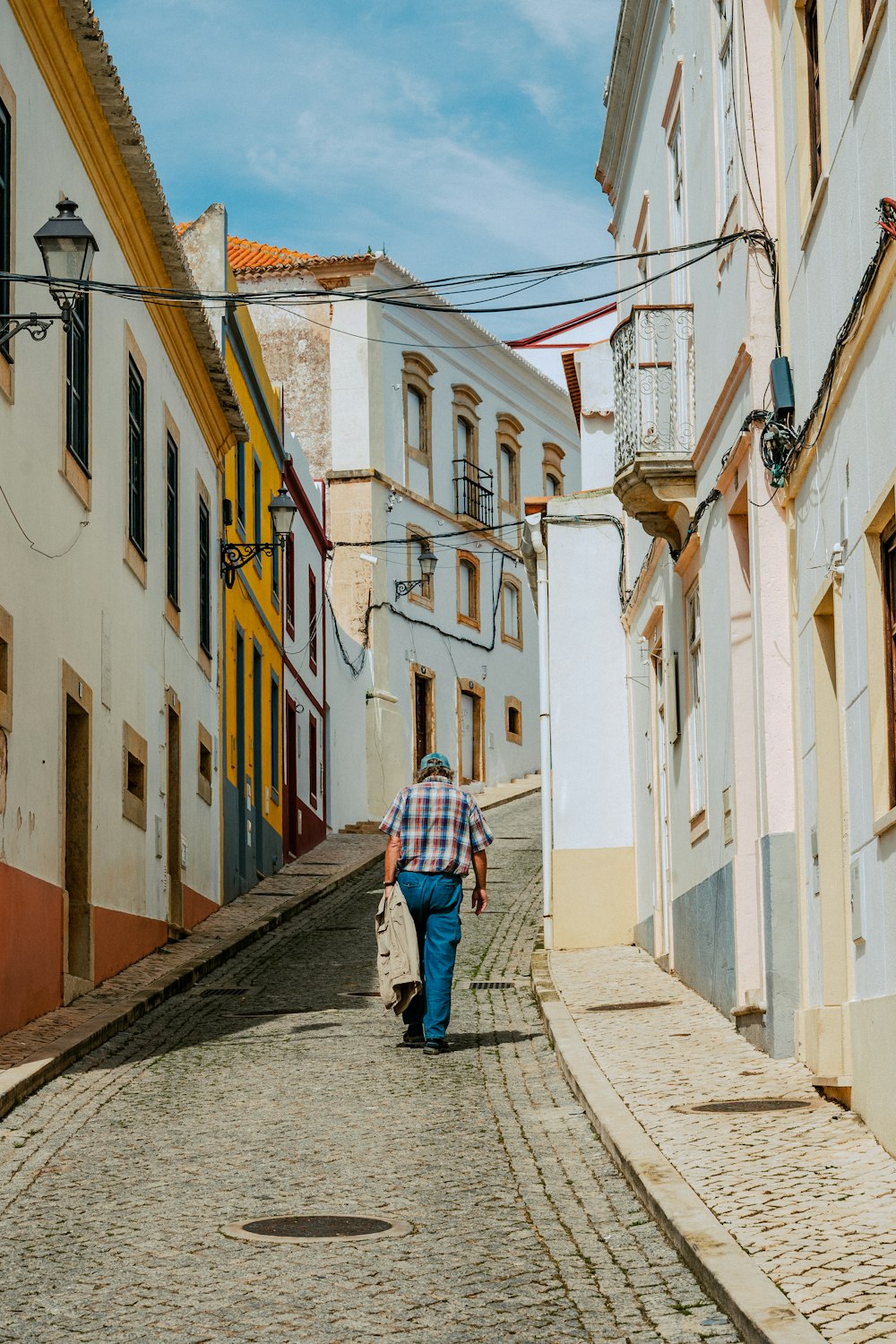 a man is walking down a cobblestone street