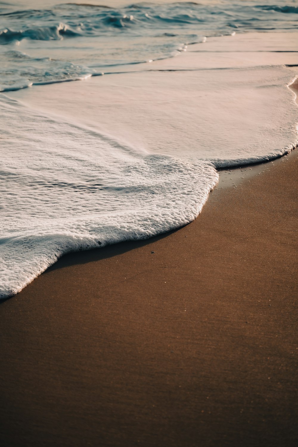 a sandy beach with waves coming in and out of the water