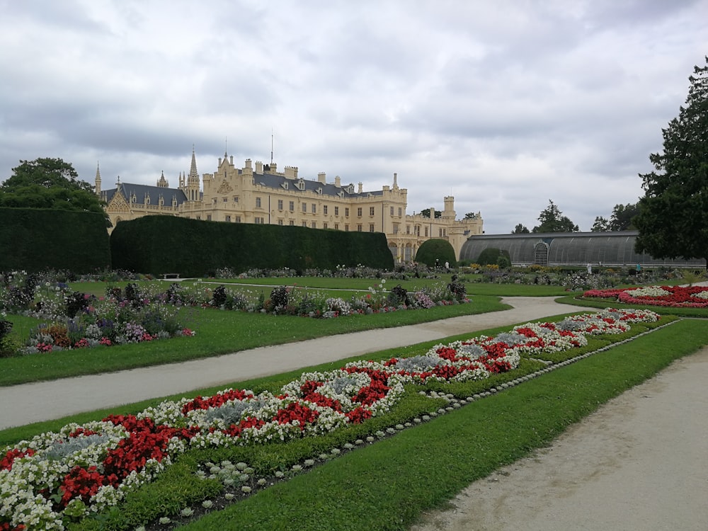 a garden with flowers and a large building in the background