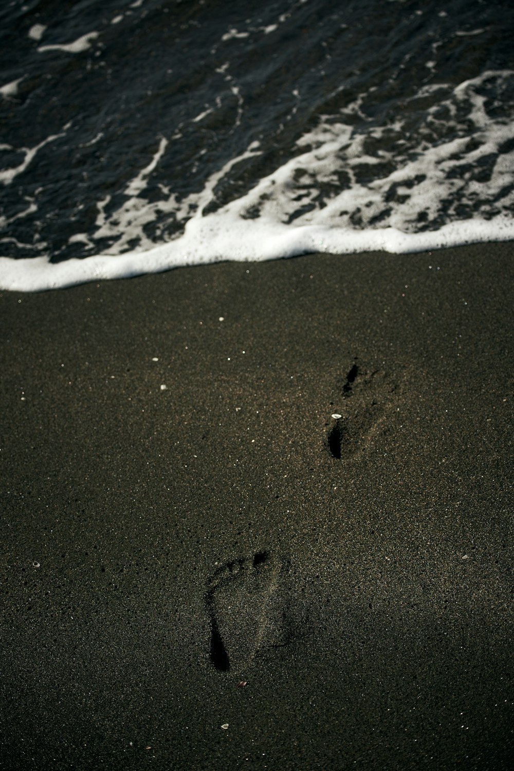 footprints in the sand of a beach next to the ocean