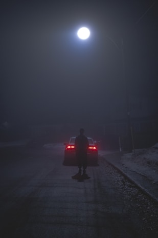 A friendly recovery driver assisting a stranded car on a quiet Leicester street at dusk.