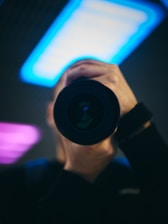 Portrait of Muhammad Shahid with camera in hand, set against a soft blurred background.