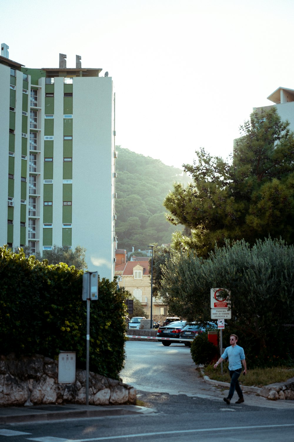 a man walking across a street next to a tall building