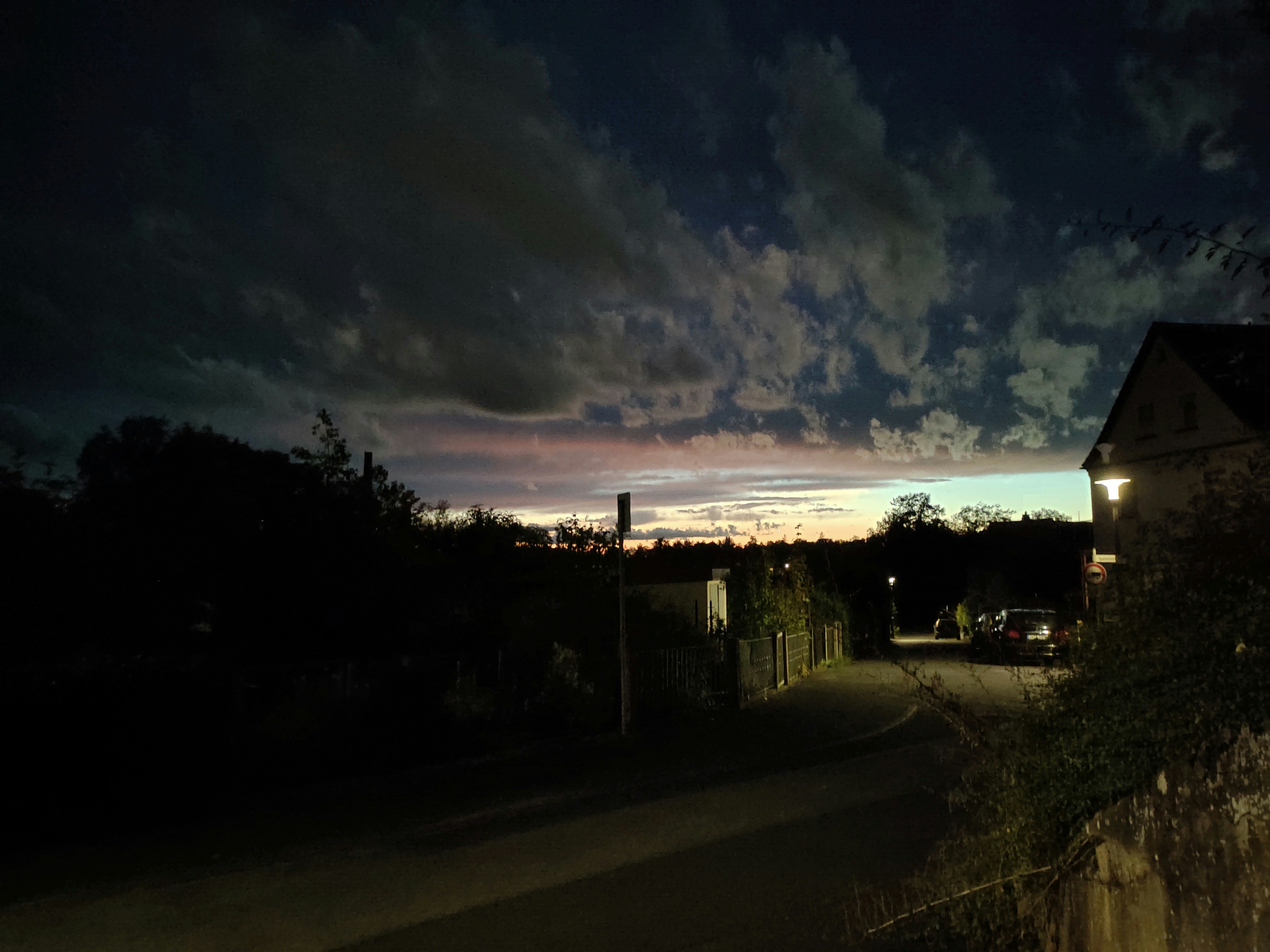 a dark street at night with clouds in the sky