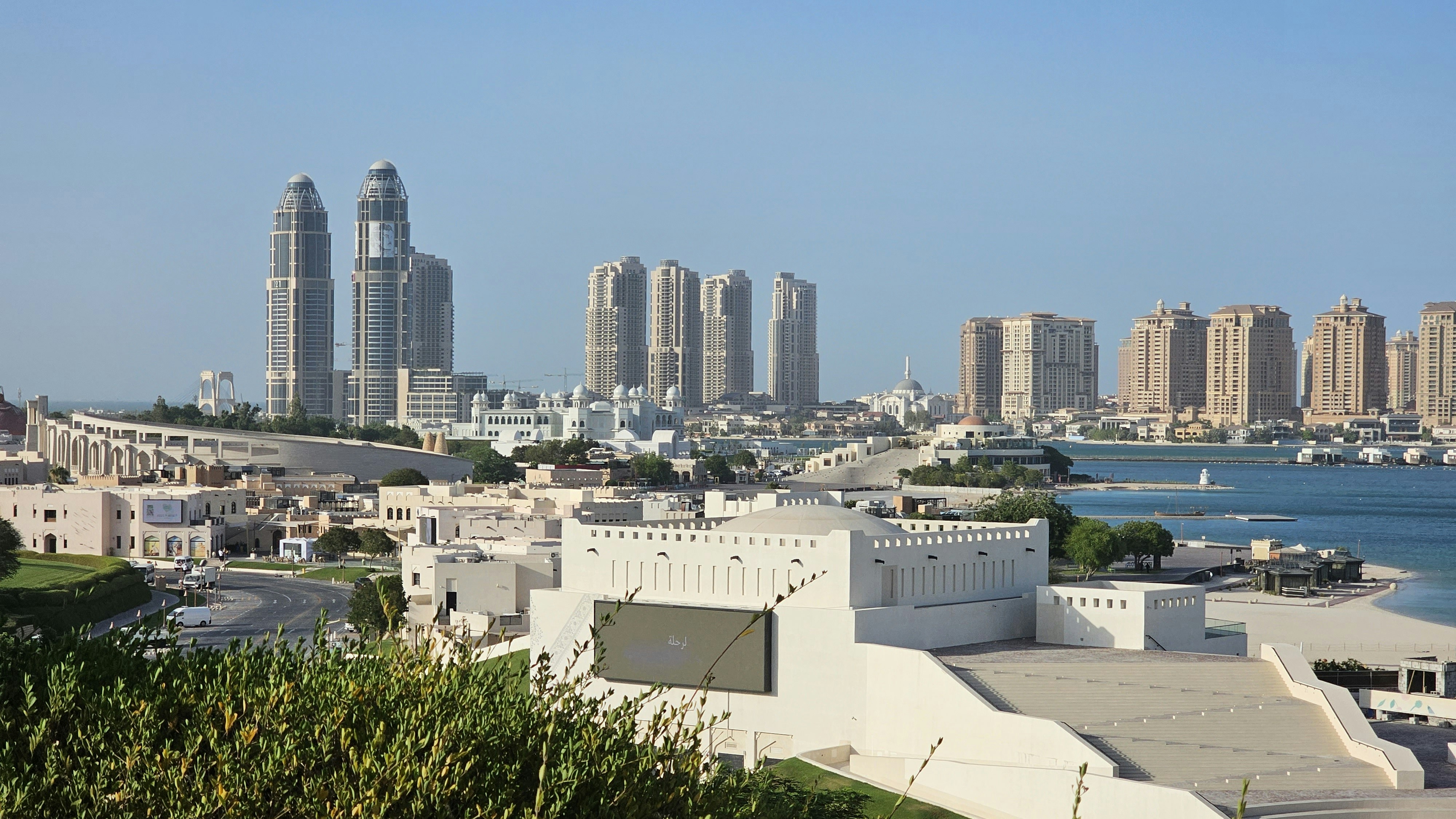 a view of a city with tall buildings and a body of water, view Qatar and i make traveling videos on my YouTube channel so if you are interested then join https://www.youtube.com/@myexperiencesreviews6616/videos