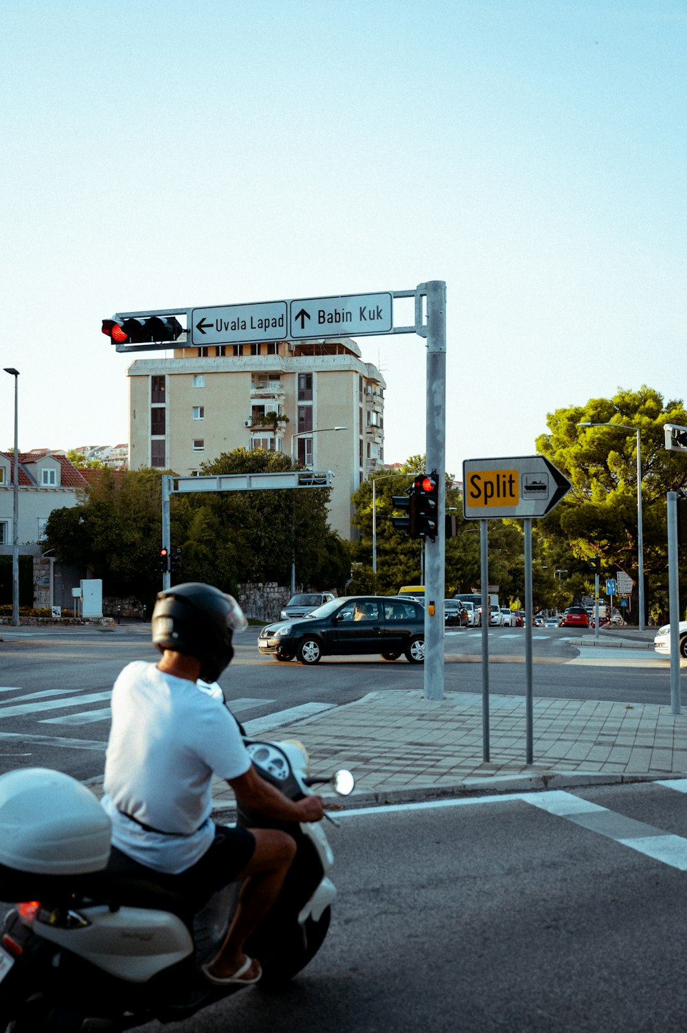 a man riding a motorcycle down a street next to a traffic light