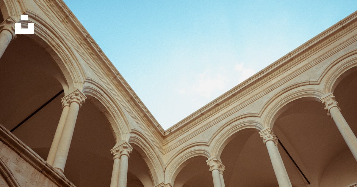 A building with arches and a clock on the wall photo – Free Rector's ...