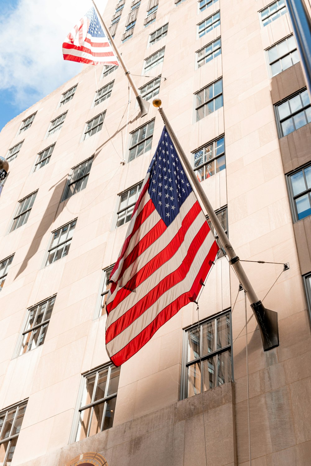 a large american flag flying in front of a tall building