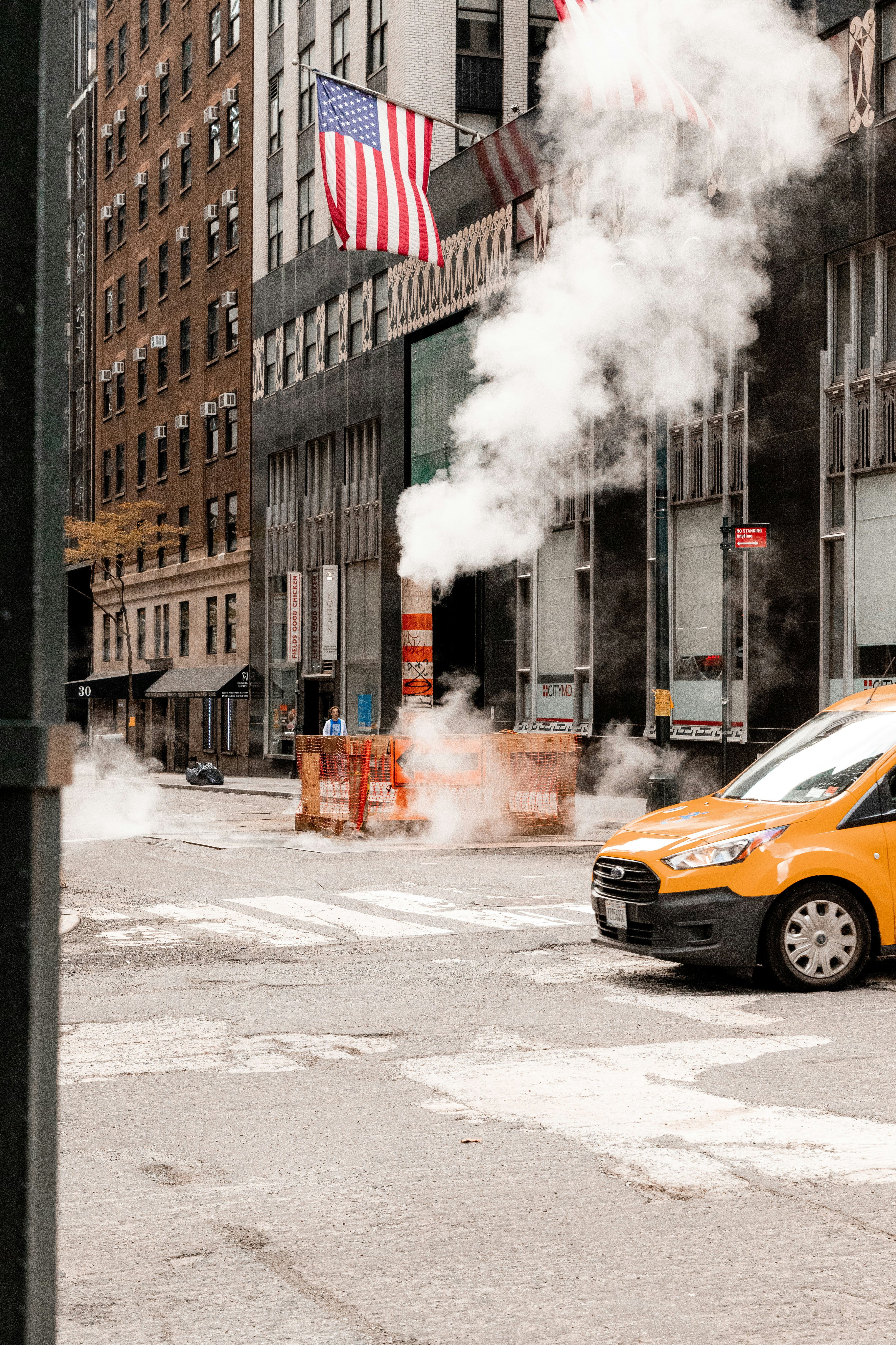 a yellow van driving down a street next to tall buildings