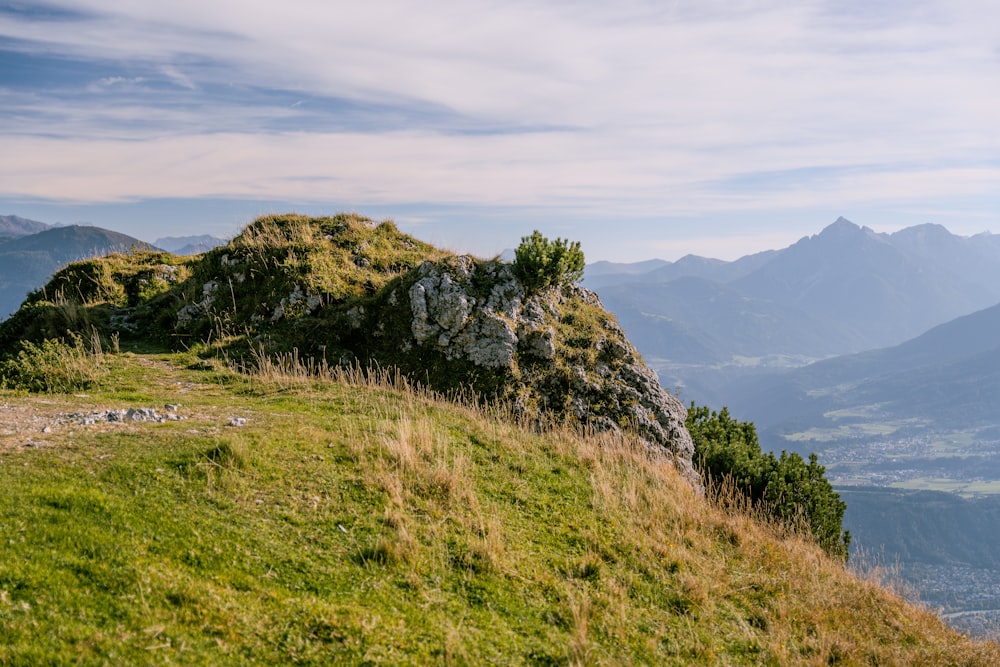 a grassy hill with a rock outcropping on top of it