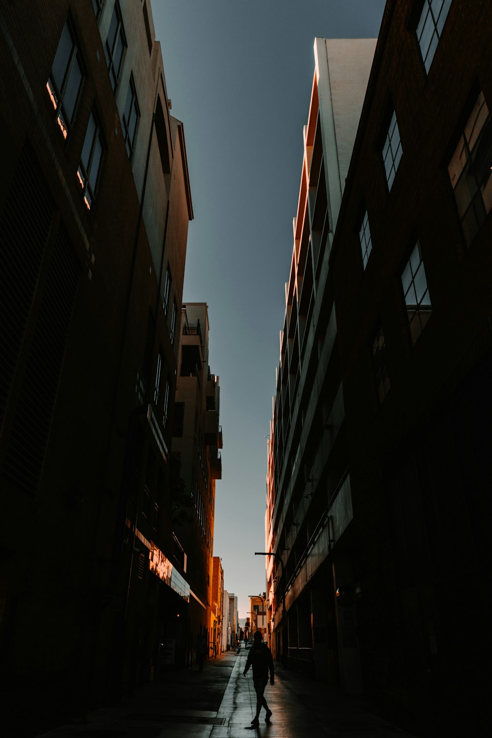 a person walking down a street next to tall buildings