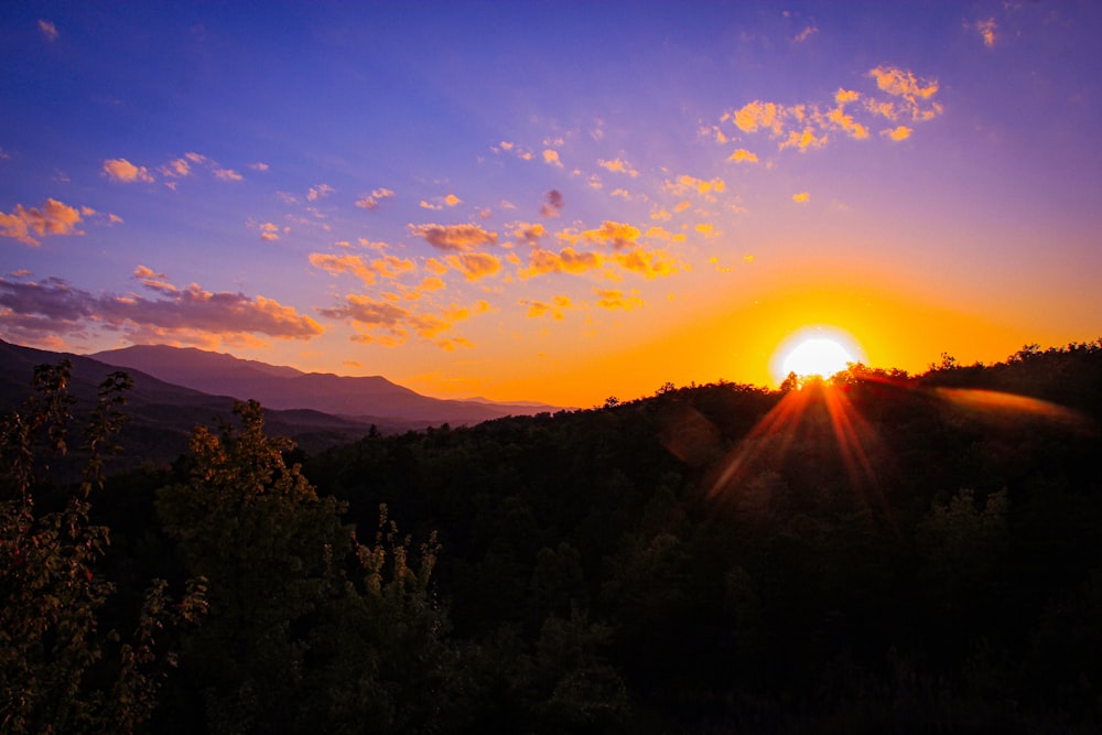 the sun is setting over a mountain range