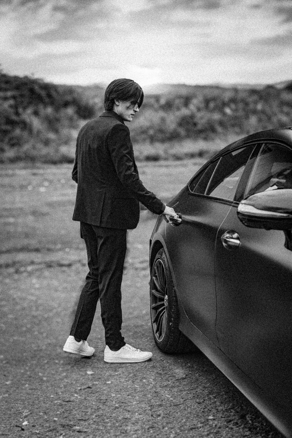 a man in a suit standing next to a car