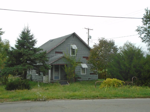 Close-up of a teardown property with an older home surrounded by mature trees.