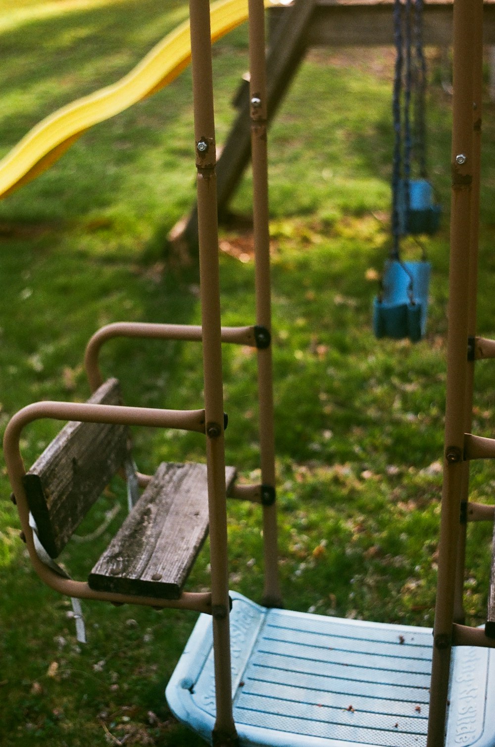 a swing set in a park with a slide in the background