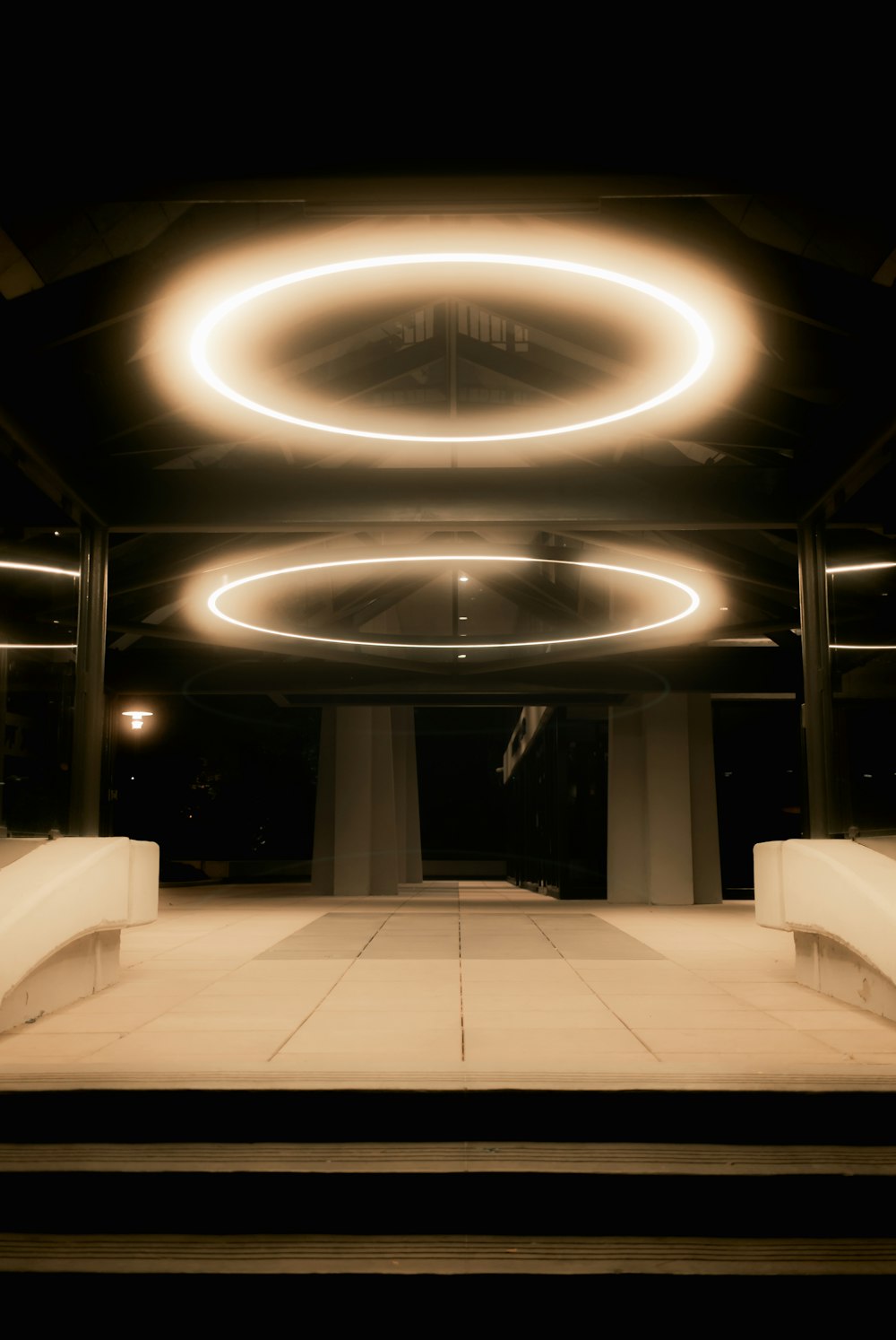 a dimly lit area with benches and circular lights