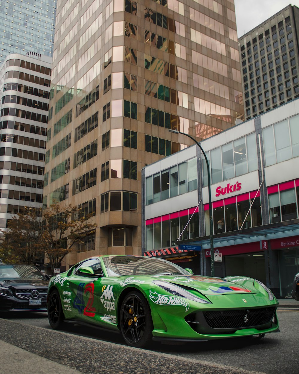 a green sports car parked in front of a tall building