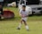 A young football player practicing dribbling on a grassy field, focused and determined.
