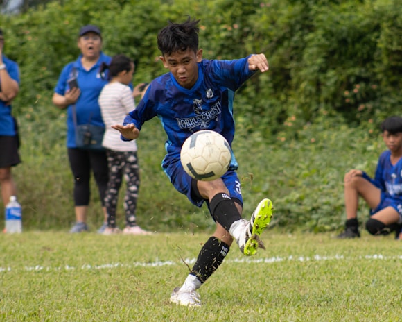 Young African football player training intensely on a vibrant, dynamic field background.