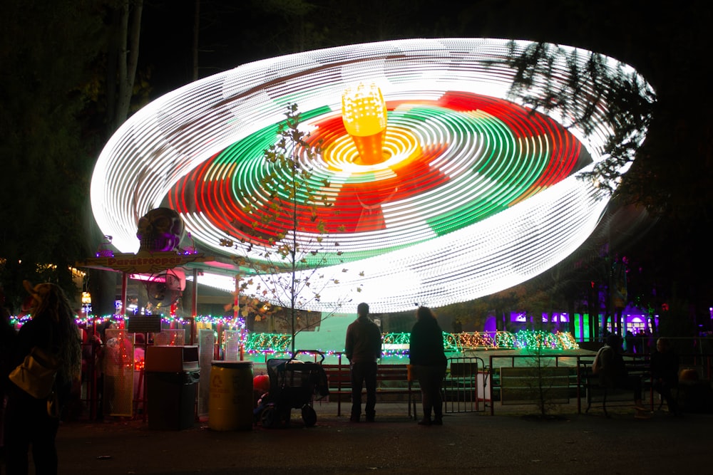 a merry go round at night with people standing around