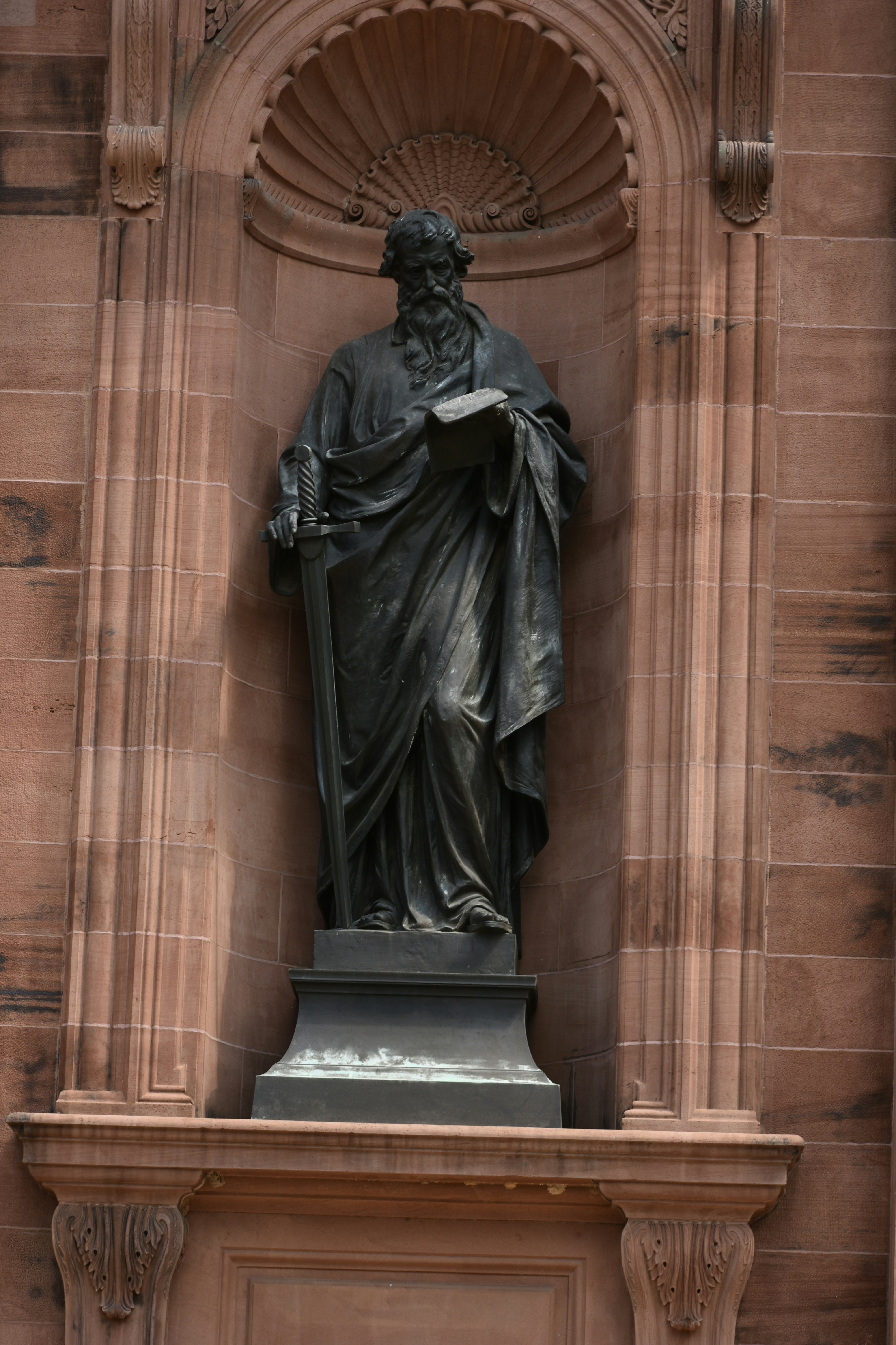 a statue of a man holding a book in front of a building