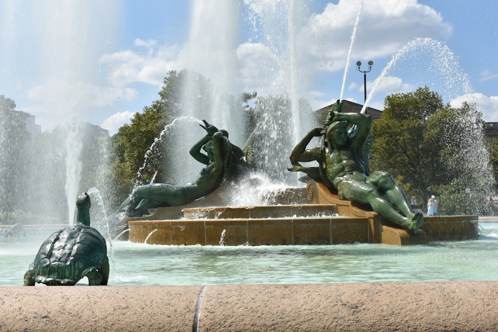 a couple of statues sitting in front of a fountain