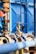 An industrial setup with numerous pipes and valves, primarily featuring shades of blue and metallic surfaces. The image captures a close-up of a valve in focus with a blurred background showing more industrial equipment and a blue structural element.