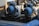 Two large blue industrial electric motors are mounted on metal frames. They are connected by black electrical cables, and the surrounding area contains various industrial components and piping. The motors appear to be part of a mechanical system used in a factory or plant setting.