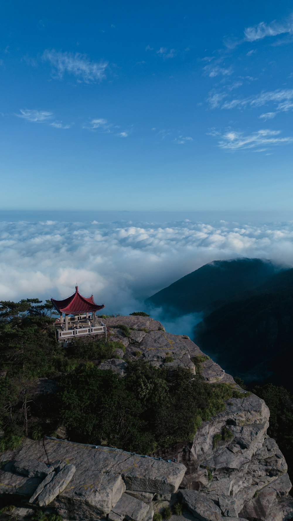 a bench sitting on top of a cliff above the clouds