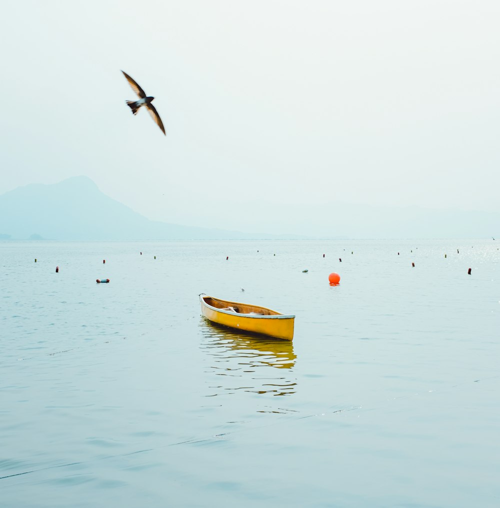 a yellow boat floating on top of a body of water