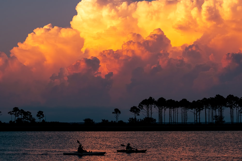 a couple of boats floating on top of a lake under a cloudy sky