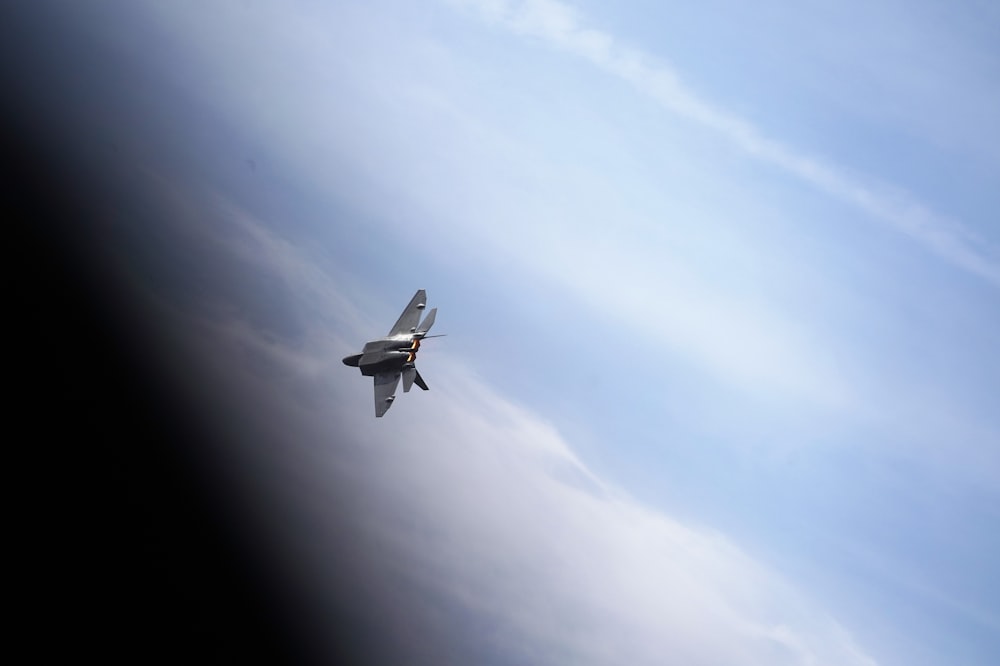 a small airplane flying through a blue cloudy sky