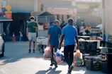 A caregiver helping with shopping bags outside a local market on a bright day.