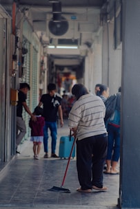 A professional cleaner sweeping the lobby floor of a modern apartment building.