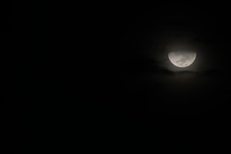 the moon is seen through the clouds in the dark sky