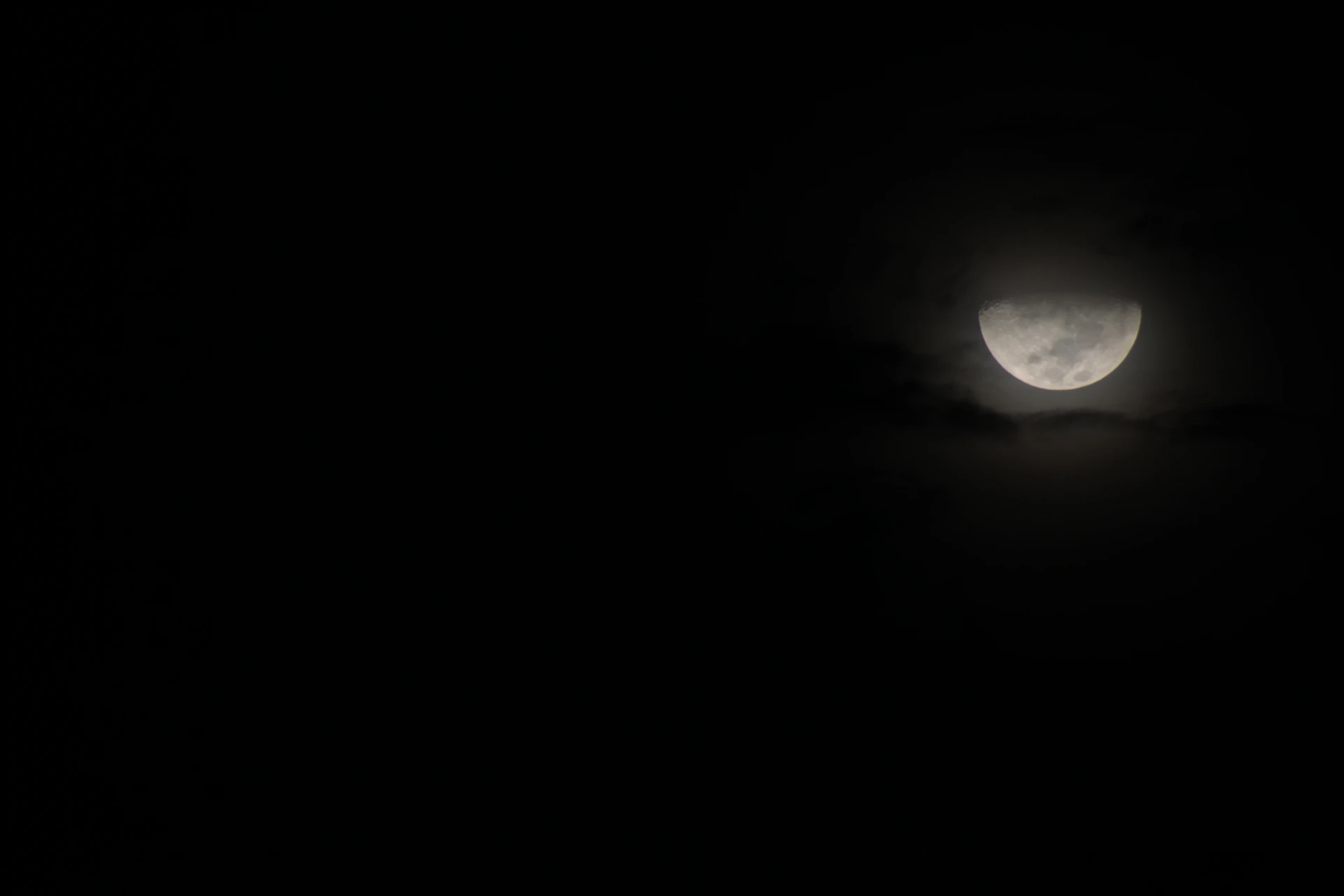 the moon is seen through the clouds in the dark sky
