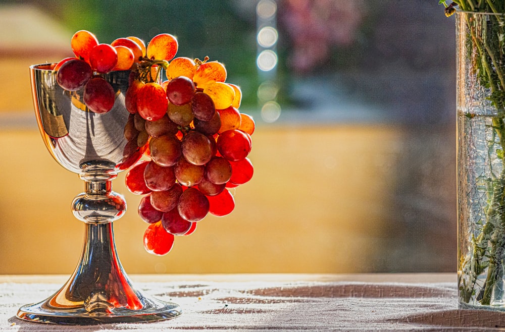 a glass vase filled with red and yellow grapes