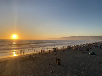 A panoramic view of Cox's Bazar beach under a golden sunset sky.