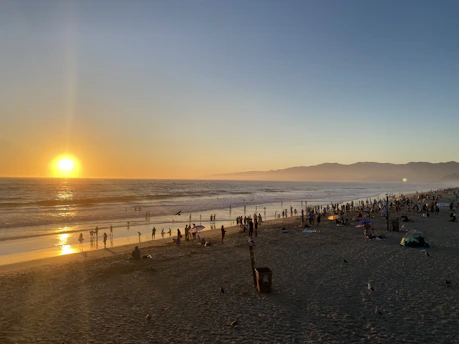 A panoramic view of Cox's Bazar beach under a golden sunset sky.