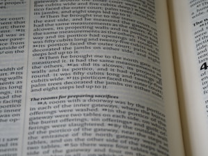 A close-up view of the pages of an open book, with text printed in black ink on off-white paper. The text appears to be formatted in two columns with some sections highlighted in bold.