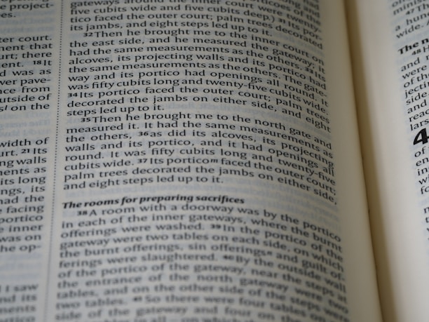A close-up view of the pages of an open book, with text printed in black ink on off-white paper. The text appears to be formatted in two columns with some sections highlighted in bold.