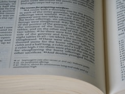 A close-up view of an open book with text describing rooms for preparing sacrifices. The pages are spread and the text includes sections and notes in smaller font.