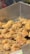A close-up view of a pile of crispy, fried food items that appear to be pieces of fried chicken or similar battered food. The texture looks crunchy and golden with shredded bits scattered around them, indicating they have been freshly fried.