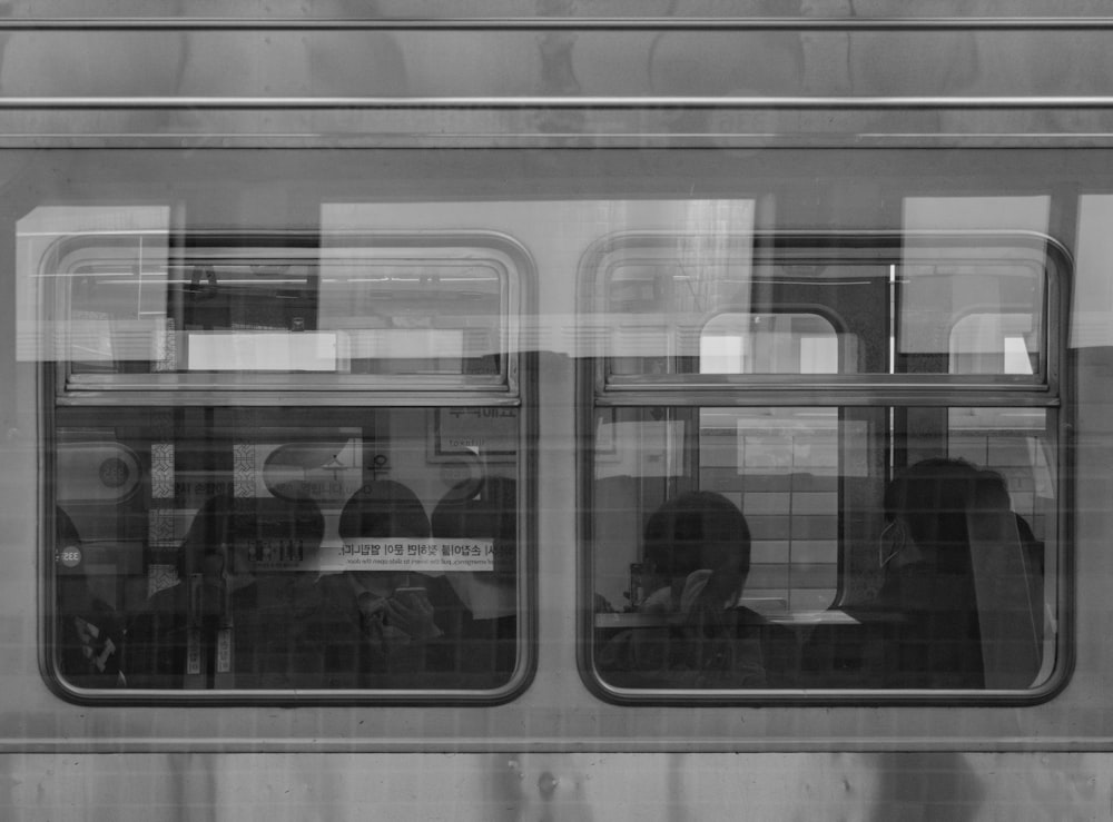 a black and white photo of people sitting on a train