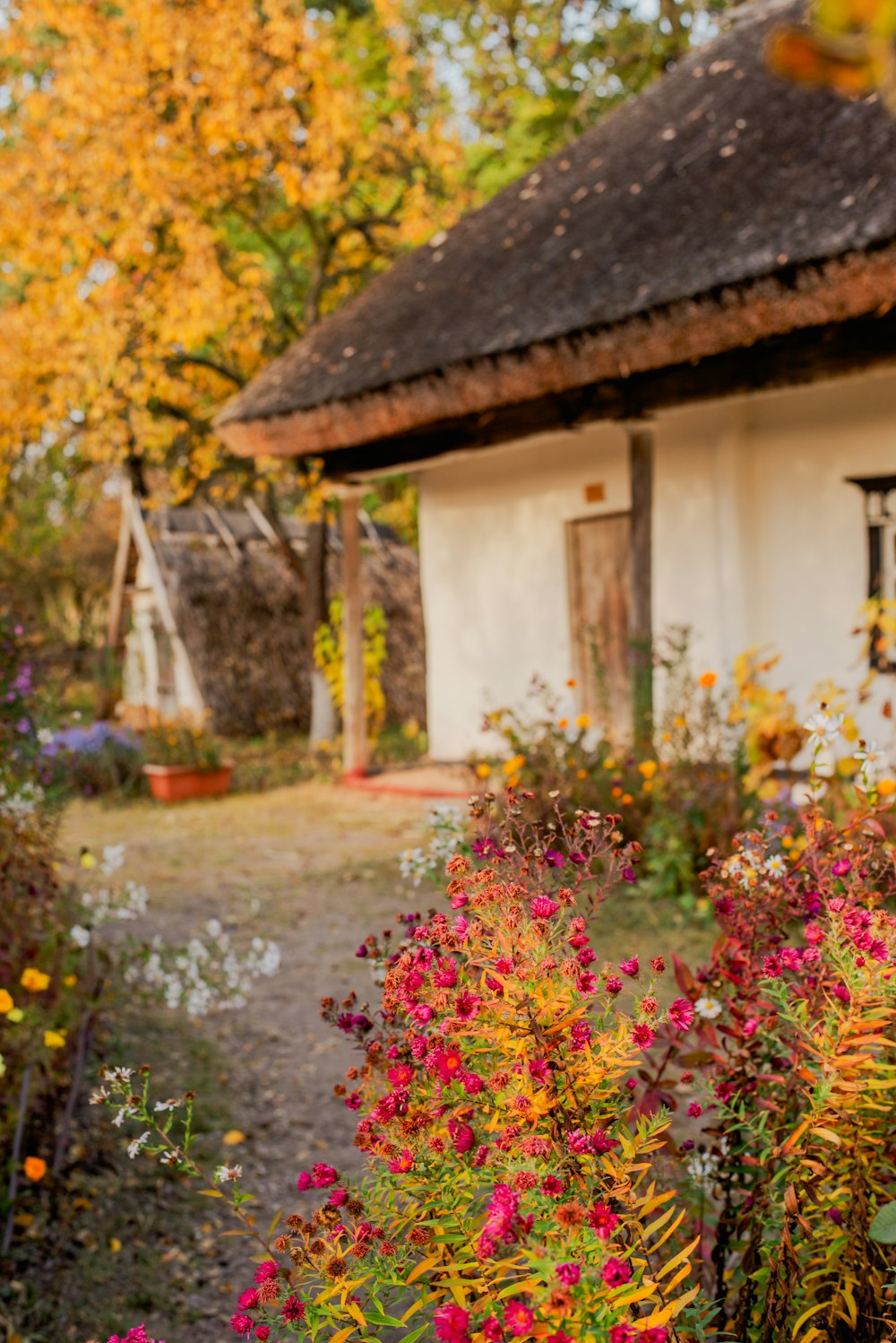 a house with a thatched roof surrounded by colorful flowers