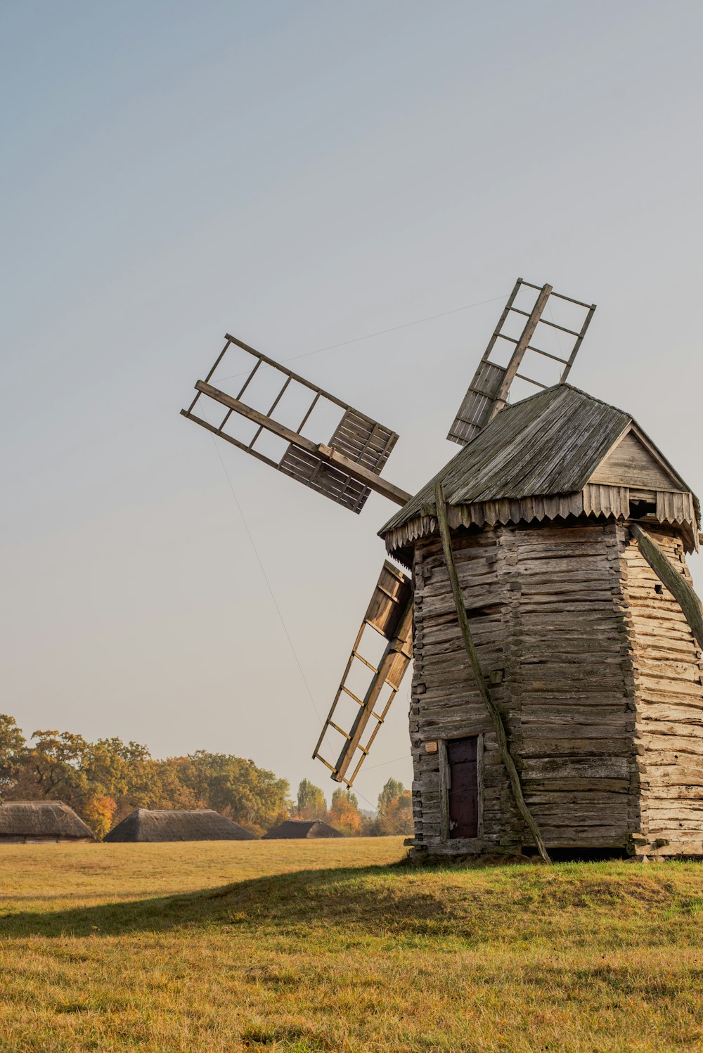 an old wooden windmill in a grassy field