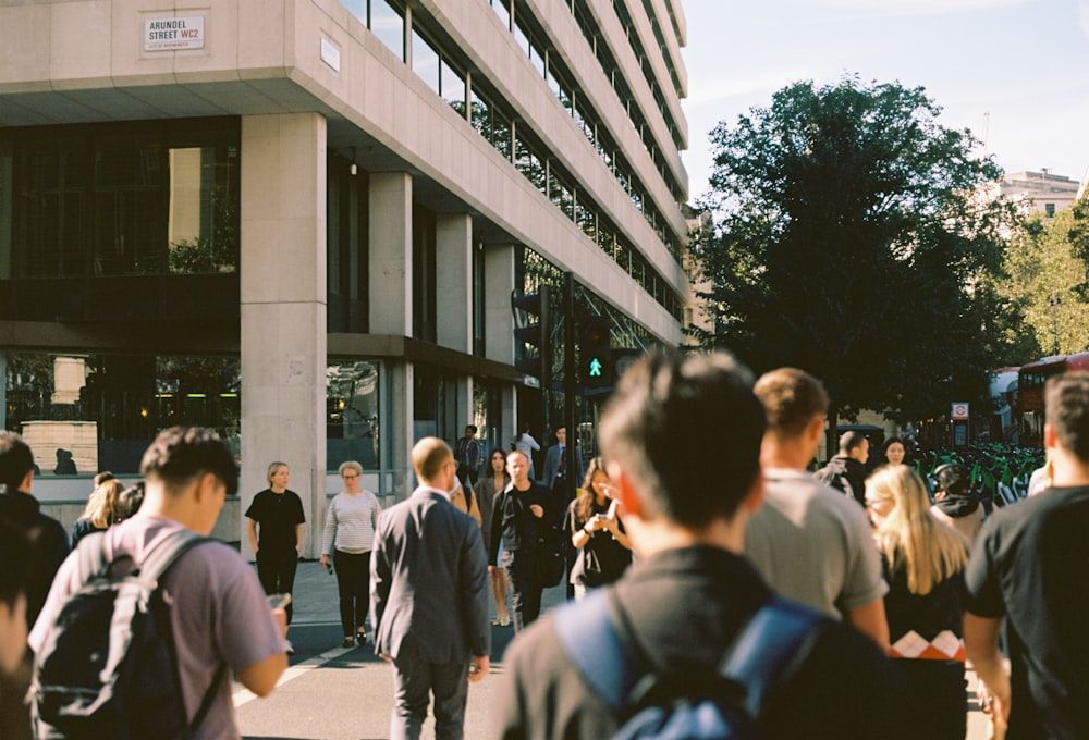 a group of people walking down a street next to a tall building