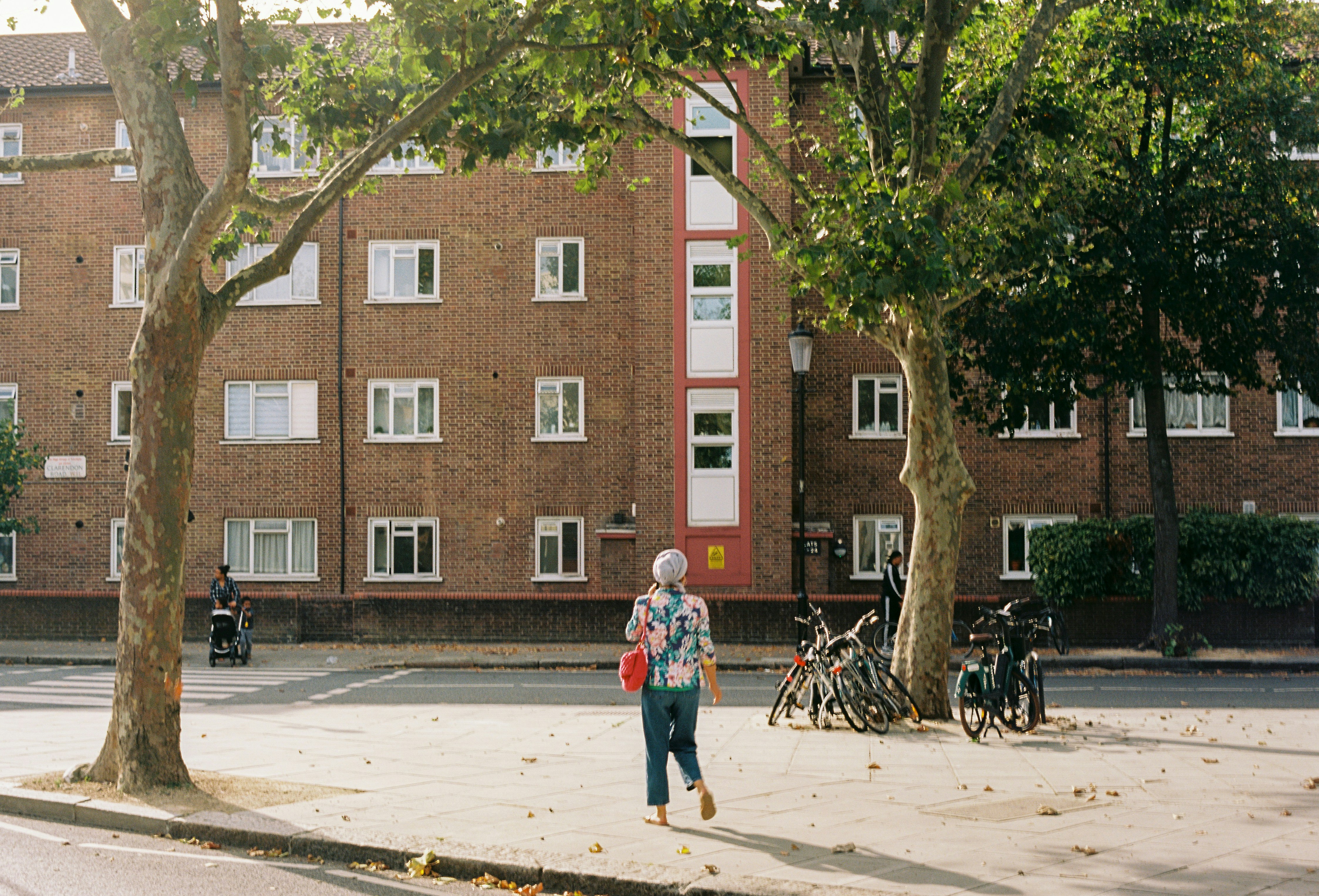 a woman walking down a street next to a tall brick building